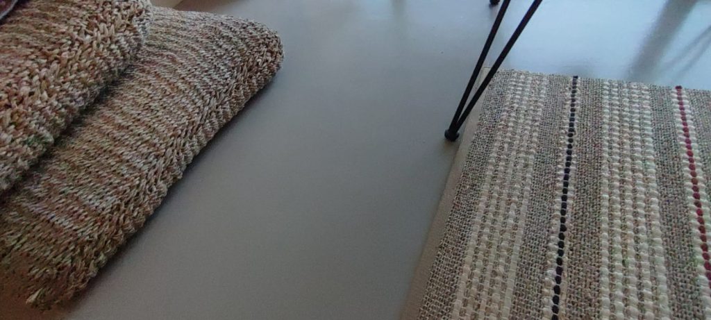 Détail d'un sol en béton ciré avec des tapis en fibres naturelles.