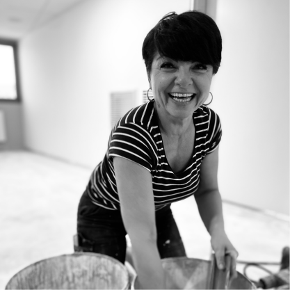 Sandra souriante appliquant du béton ciré, symbolisant expertise et passion pour le métier.