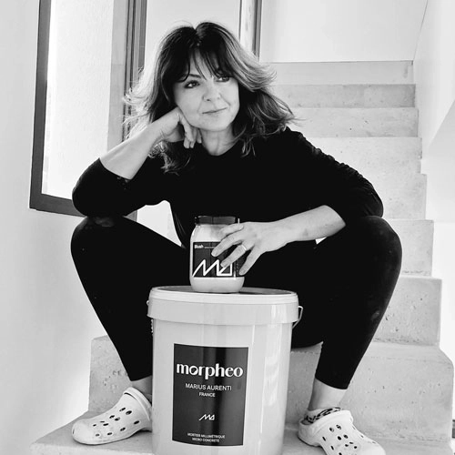 Sandra Parietti, experte en béton ciré, assise sur un escalier en béton ciré avec des produits Marius Aurenti