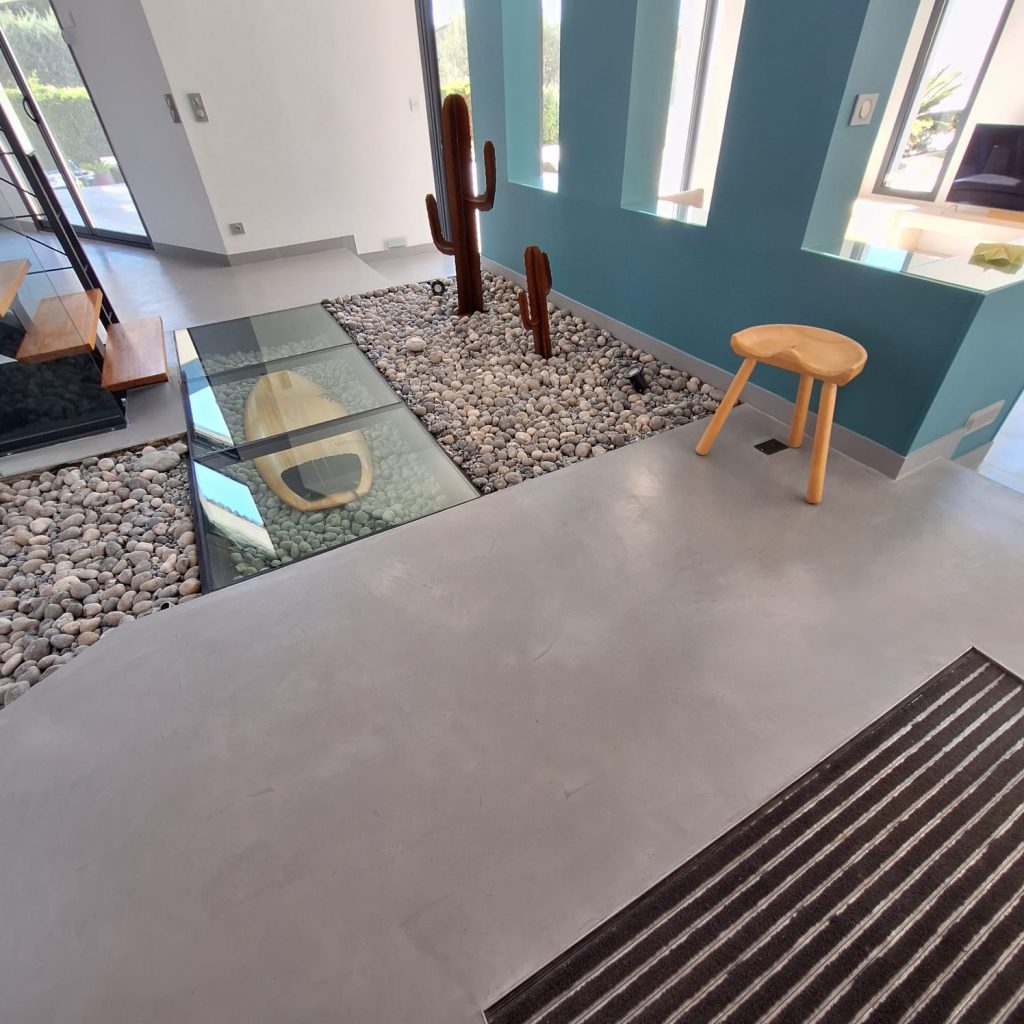 Intérieur moderne avec sol en béton ciré et éléments décoratifs en galets et verre.
