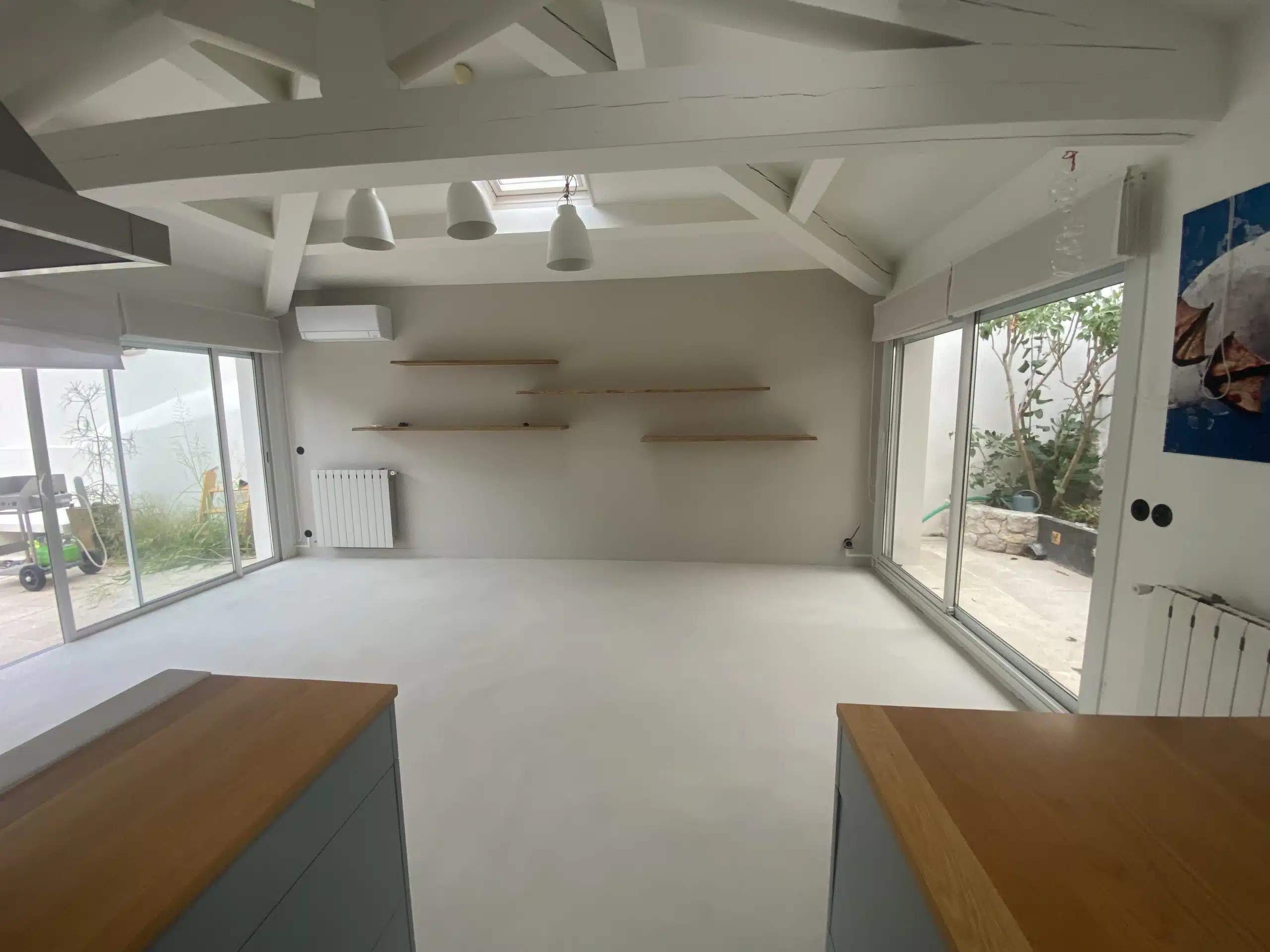 Vue d'une cuisine avec sol en béton ciré et poutres blanches