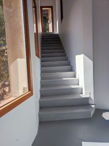 Escalier droit en béton ciré gris foncé dans un intérieur lumineux