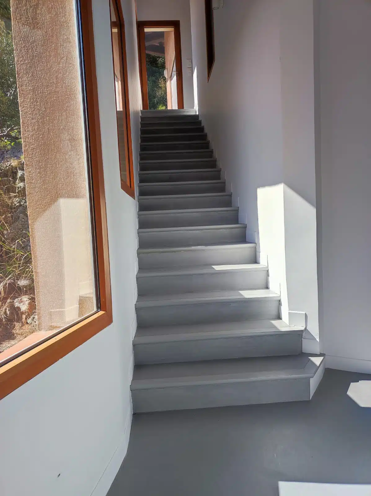 Escalier droit en béton ciré gris foncé dans un intérieur lumineux