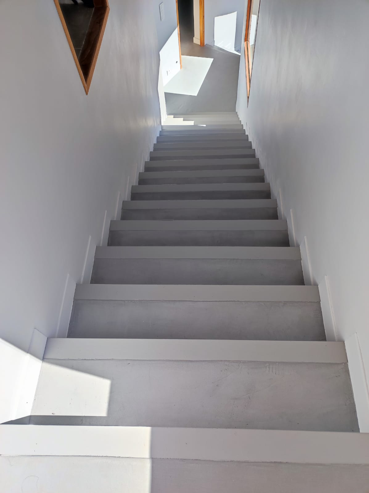 Escalier droit avec marches en béton ciré et murs blancs