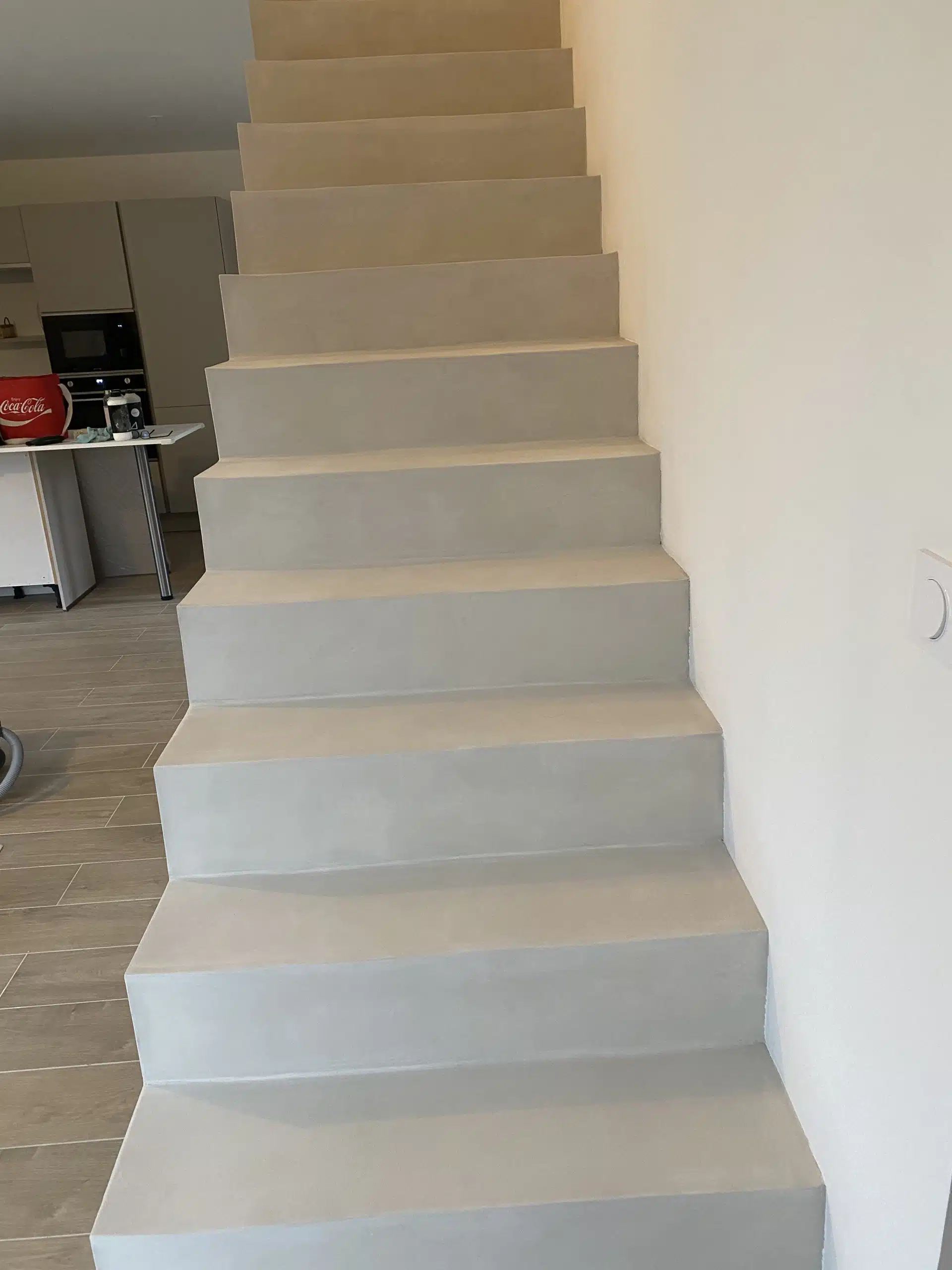 Escalier suspendu en béton ciré après pose, avec murs clairs.