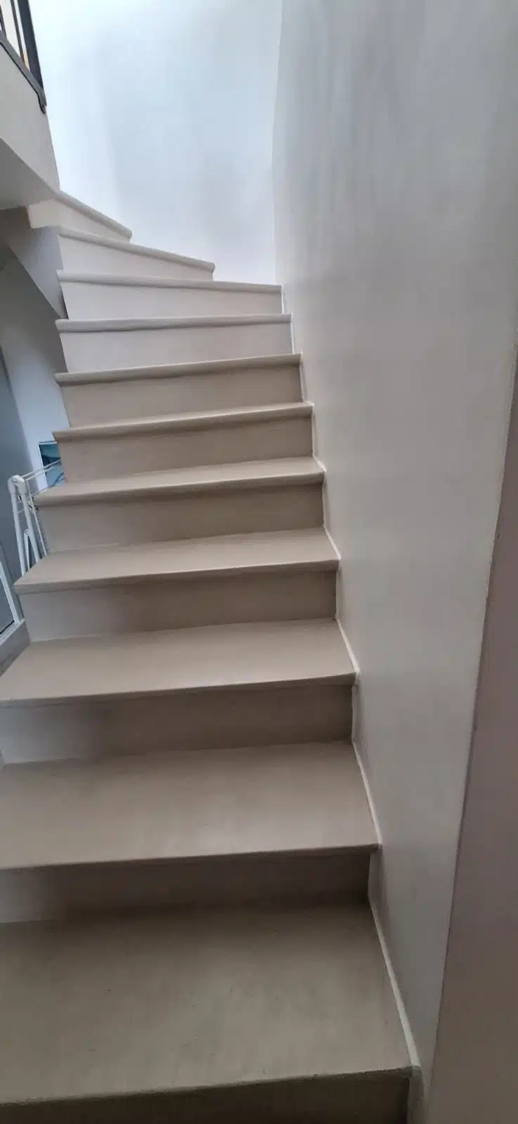 Escalier tournant en béton ciré blanc avec rambarde