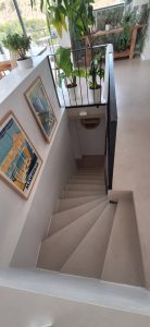 Vue d'un escalier en béton ciré avec des plantes et des affiches