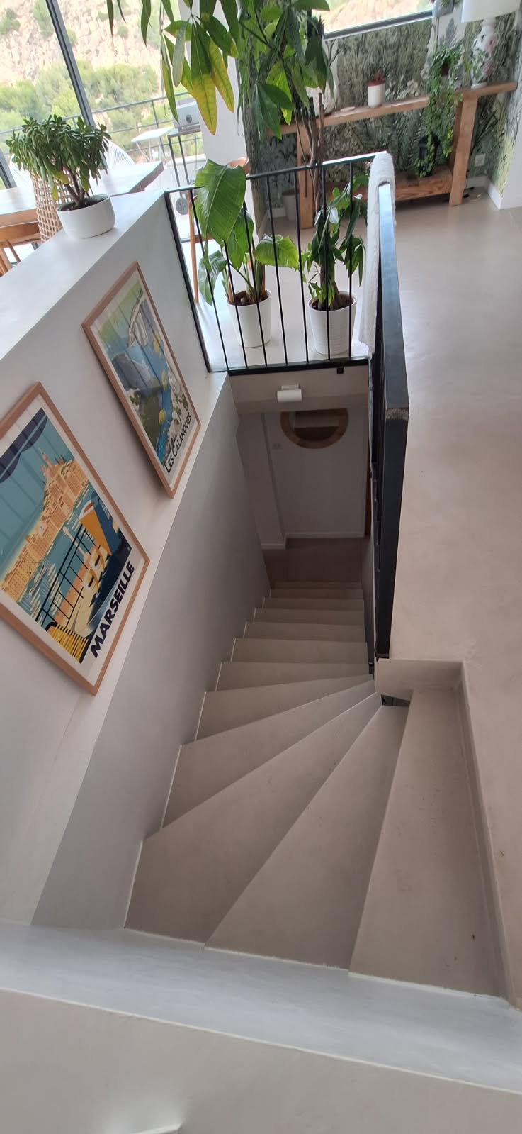 Vue d'un escalier en béton ciré avec des plantes et des affiches