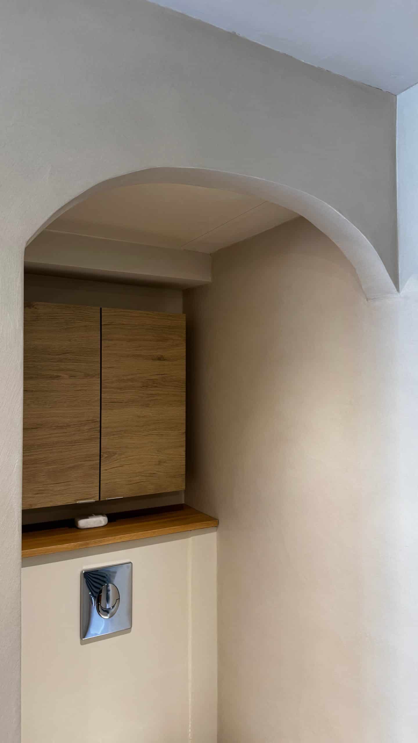 Vue d'un coin de salle de bain avec béton ciré et mobilier en bois