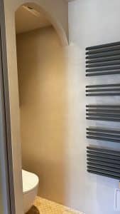 Vue d'une salle de bain avec finition en béton ciré et radiateur