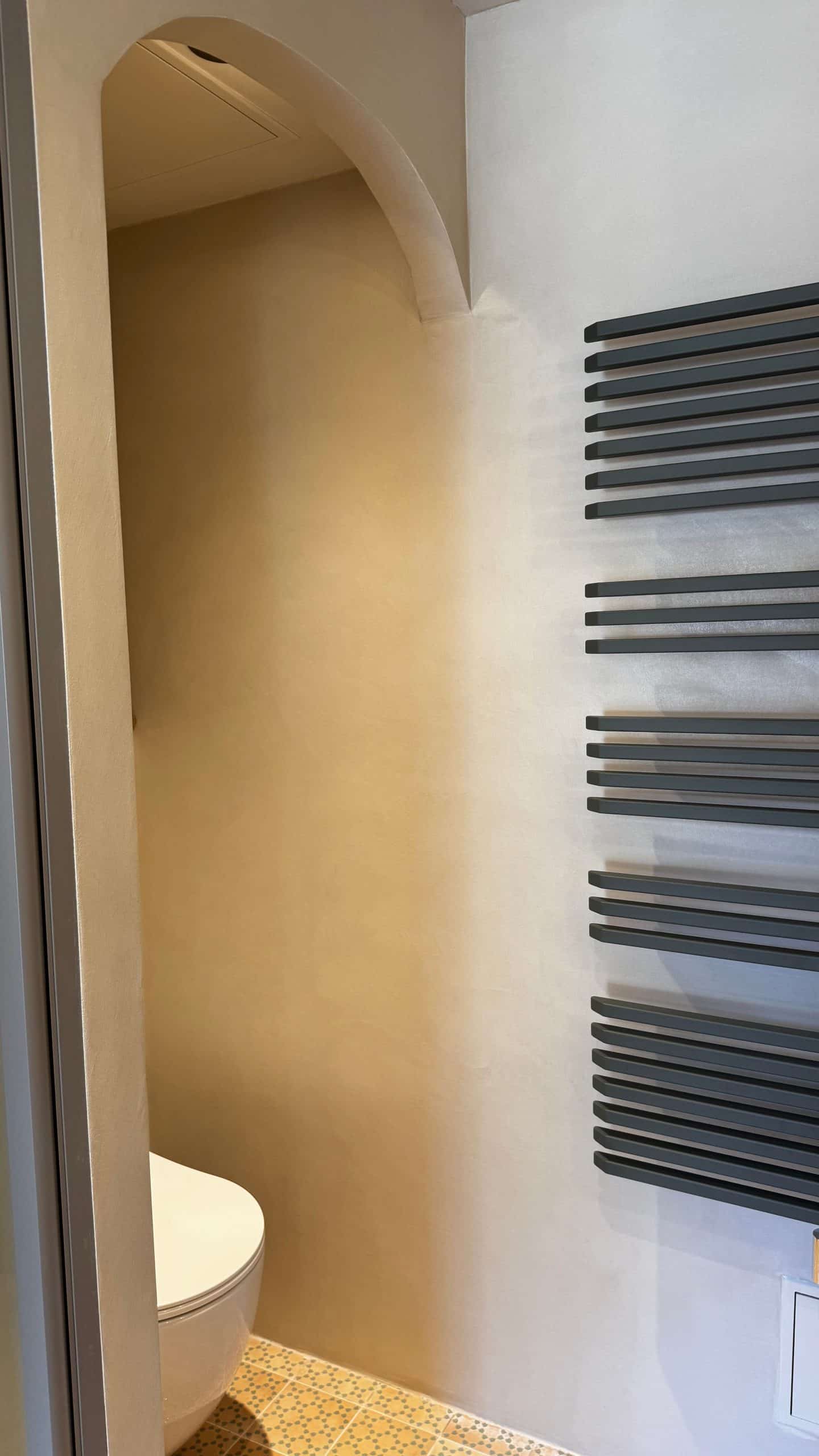Vue d'une salle de bain avec finition en béton ciré et radiateur