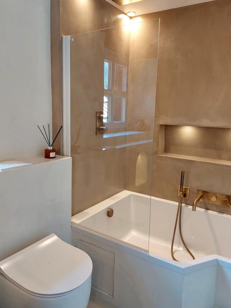 Salle de bain avec baignoire et robinetterie dorée en béton ciré