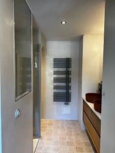 Salle de bain moderne avec béton ciré et mobilier en bois.