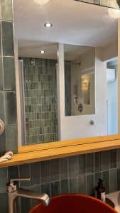 Salle de bain avec béton ciré, miroir et douche en verre.