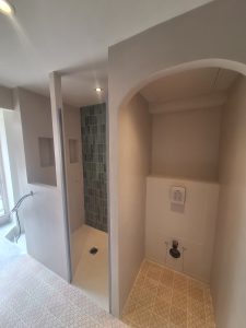 Salle de bain avec douche à l'italienne en béton ciré et carrelage.