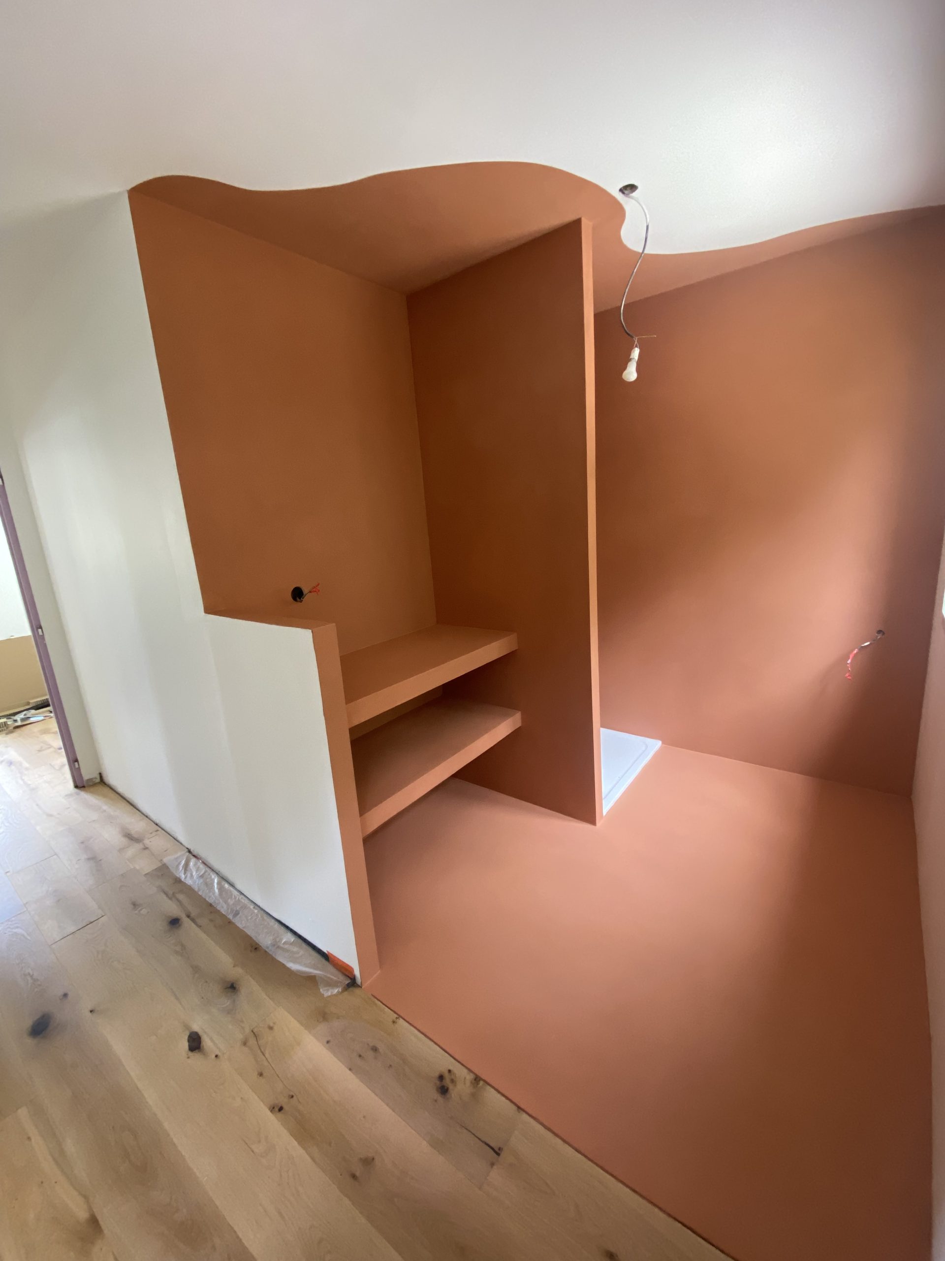 Intérieur d'une salle de bain avec un meuble en béton ciré couleur terracotta.