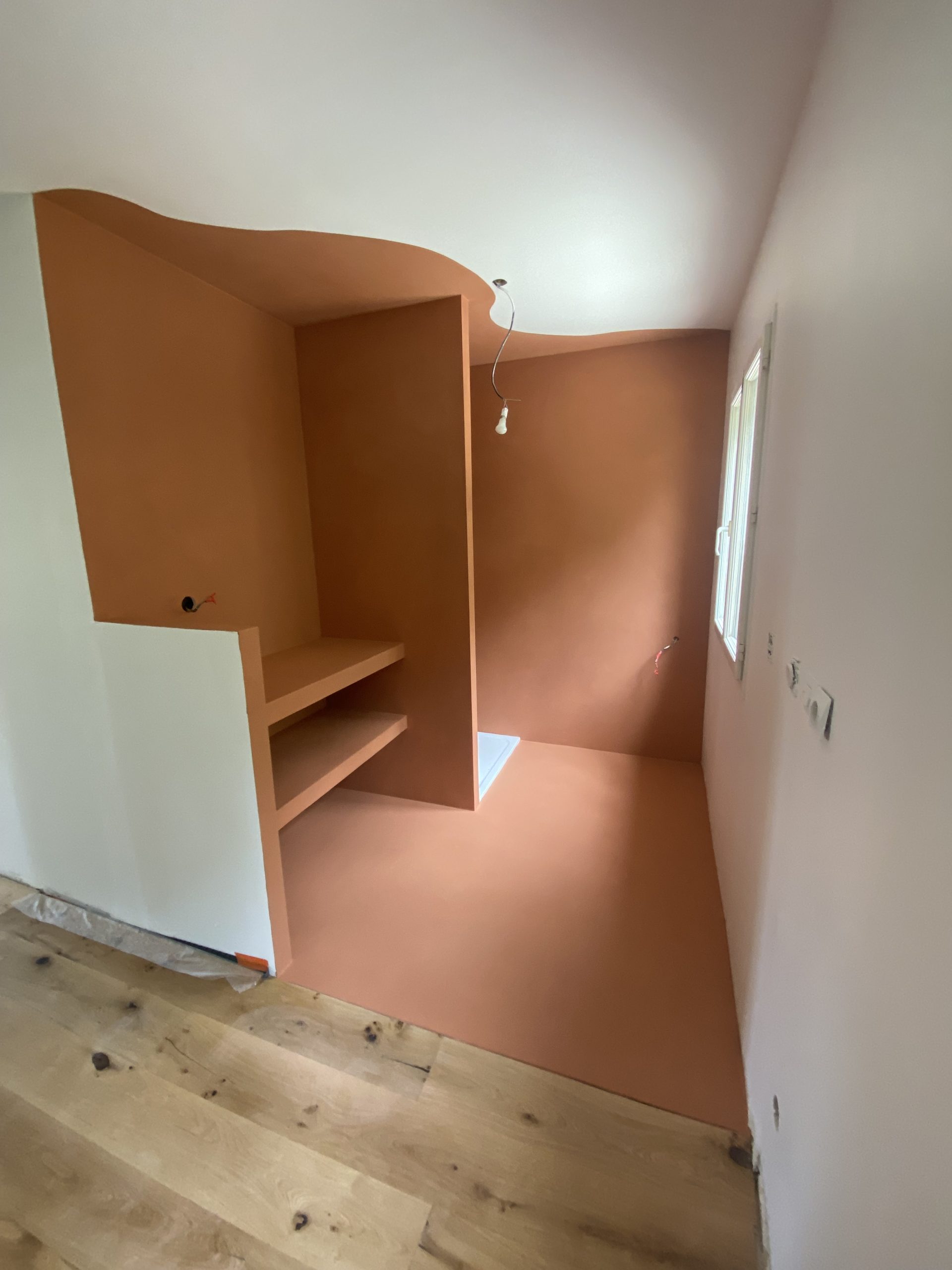 Salle de bain avec mur en béton ciré couleur terracotta en cours de finition