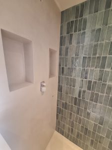 Vue d'une salle de bain avec murs en béton ciré et carrelage zellige