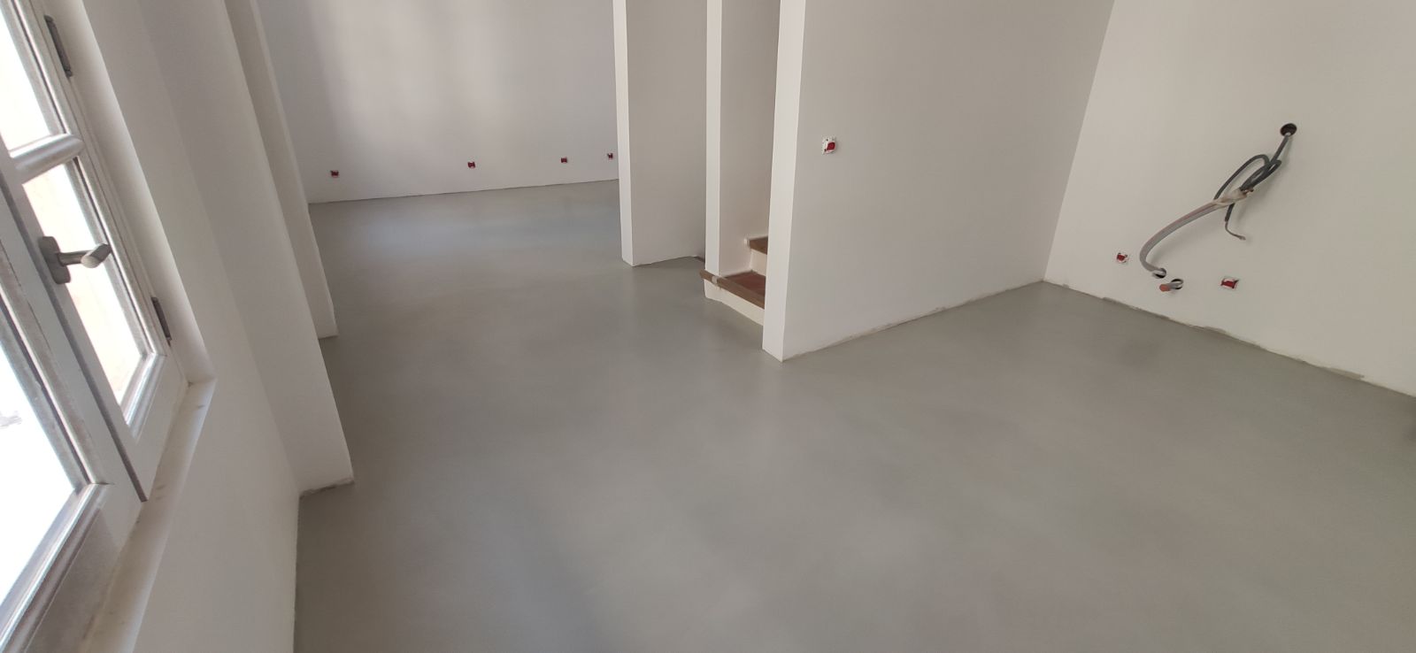 Chantier de béton ciré en cours dans une maison en rénovation : sol fraîchement taloché, murs en attente de finition et boîtiers électriques encore apparents — BTONBYSANDRA en PACA