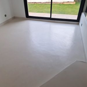 Sol en béton ciré dans une pièce lumineuse avec baie vitrée