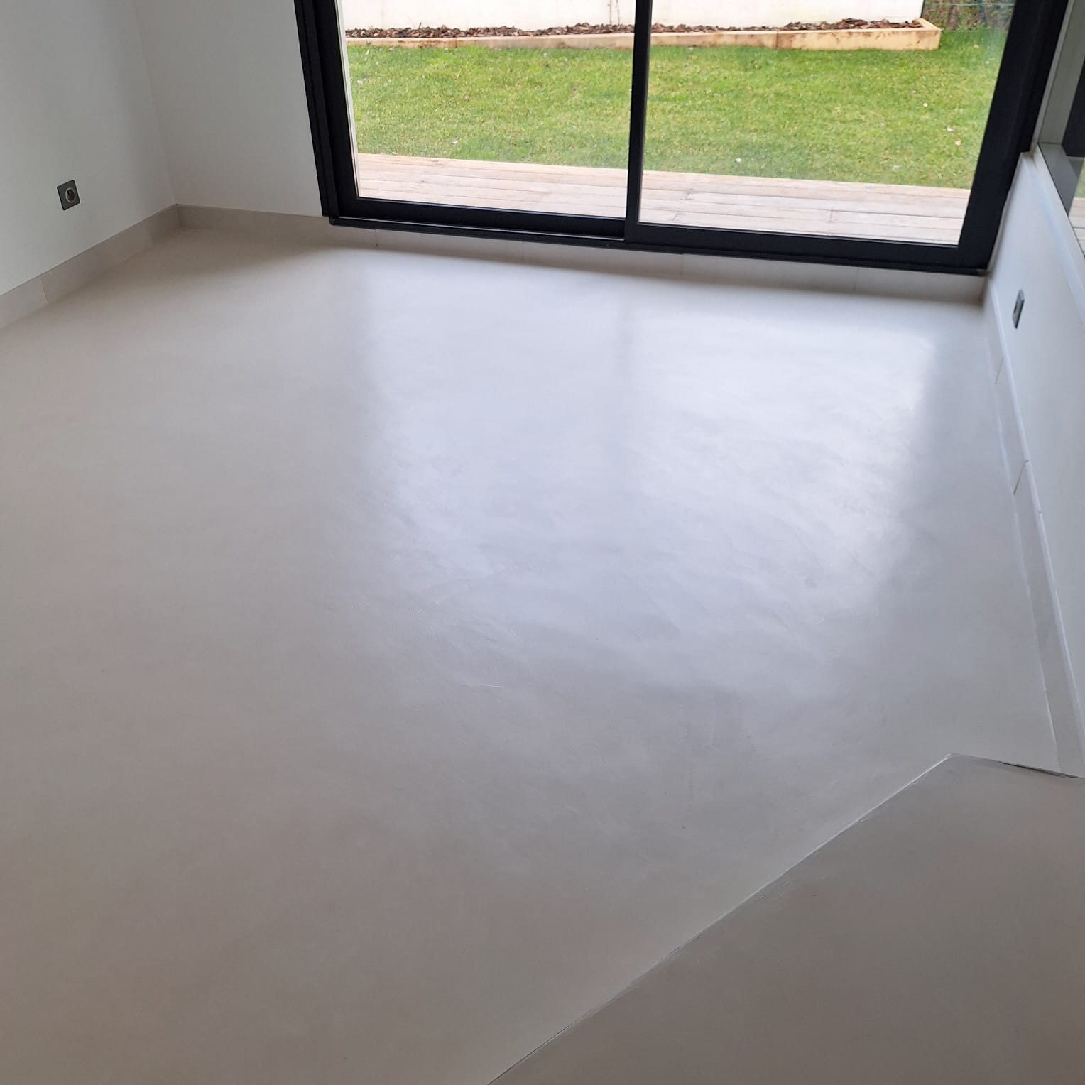 Sol en béton ciré dans une pièce lumineuse avec baie vitrée