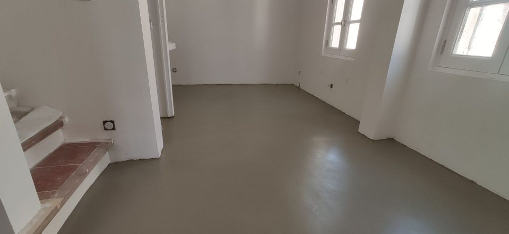 Image d'un sol en béton ciré dans une pièce avec des murs blancs.