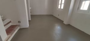 Image d'un sol en béton ciré dans une pièce avec des murs blancs.