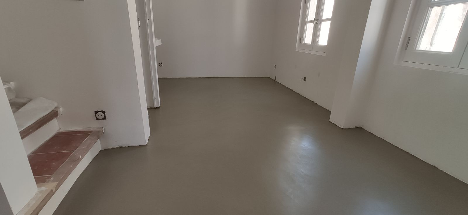 Image d'un sol en béton ciré dans une pièce avec des murs blancs.