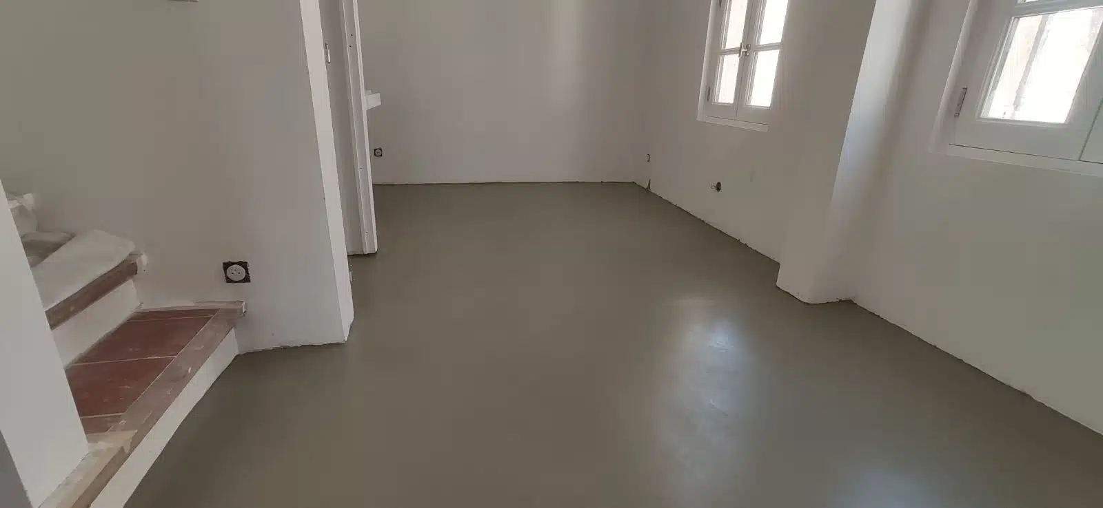 Image d'un sol en béton ciré dans une pièce avec des murs blancs.
