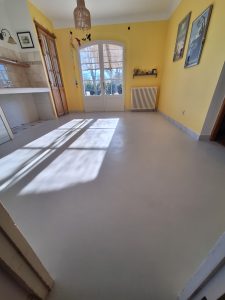 Sol en béton ciré dans une pièce lumineuse avec murs jaunes