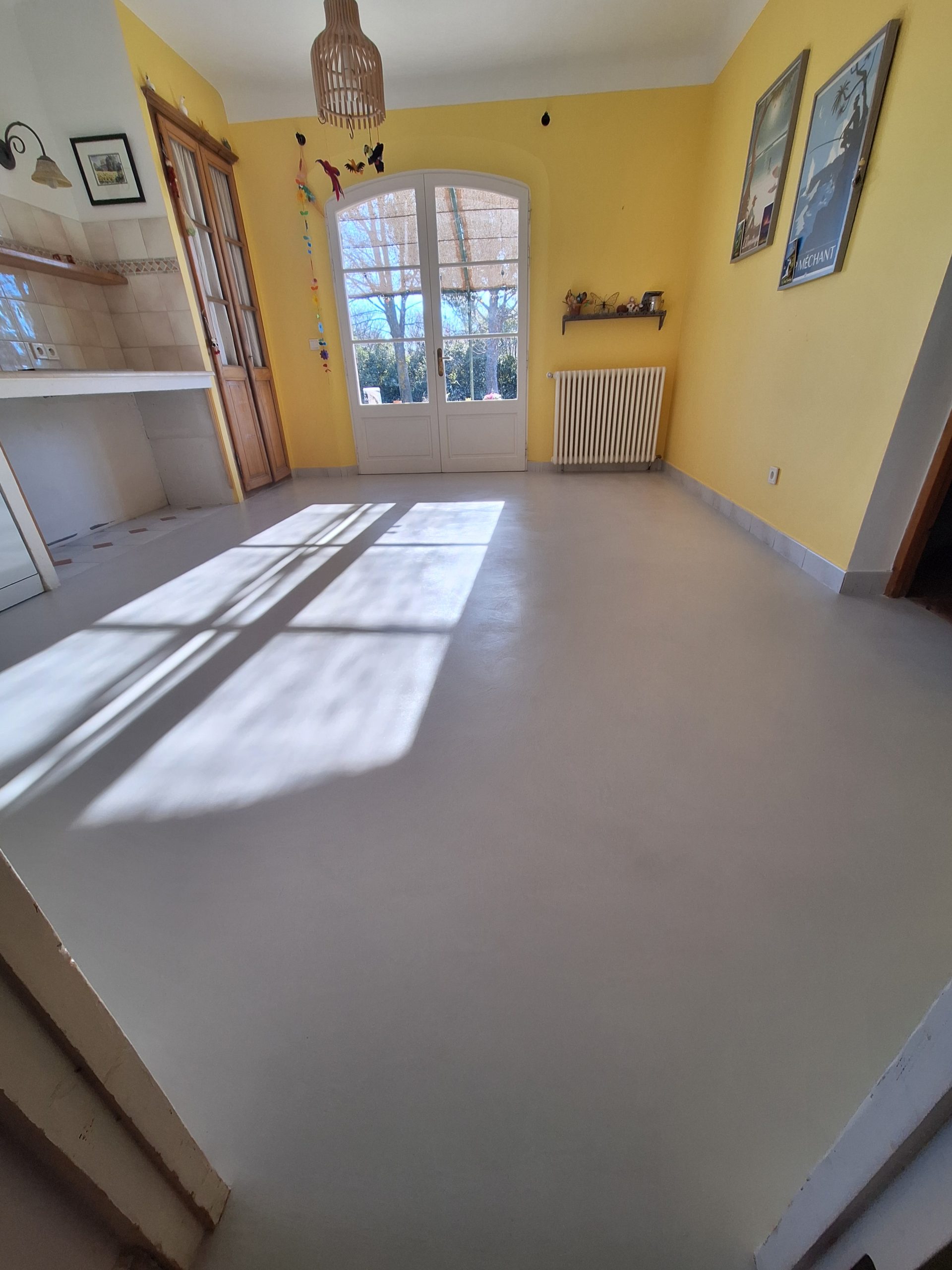 Sol en béton ciré dans une pièce lumineuse avec murs jaunes