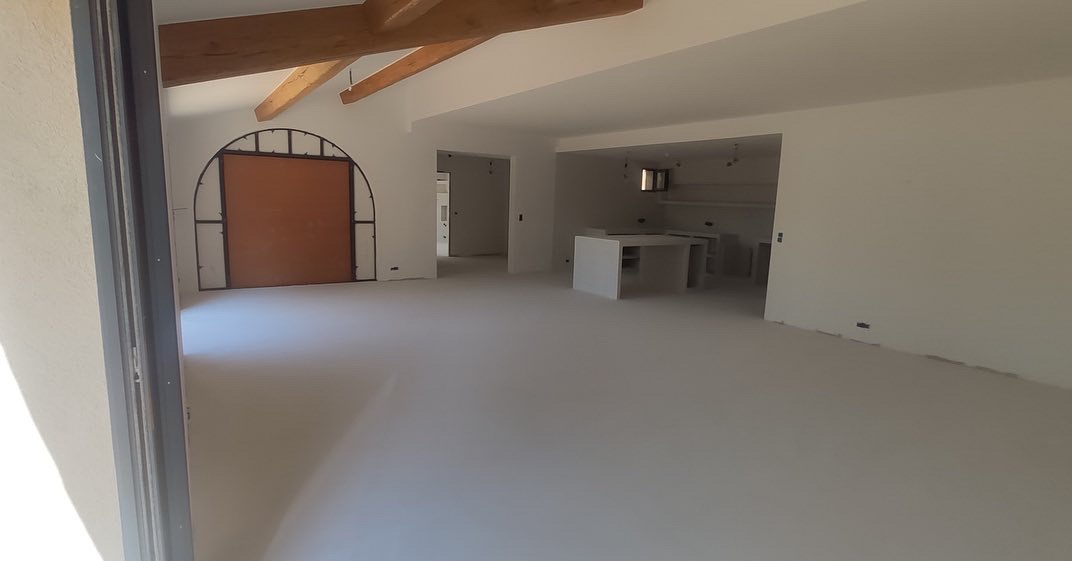 Intérieur d'une pièce avec sol en béton ciré et poutres en bois