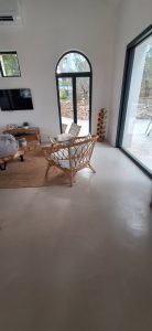 Sol en béton ciré dans un salon lumineux avec fauteuil en rotin.