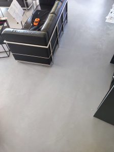 Sol en béton ciré dans un salon avec canapé Le Corbusier et mobilier design