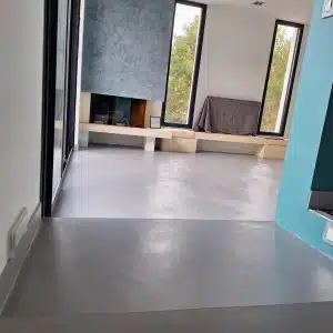 Sol en béton ciré dans un salon avec cheminée et fenêtres