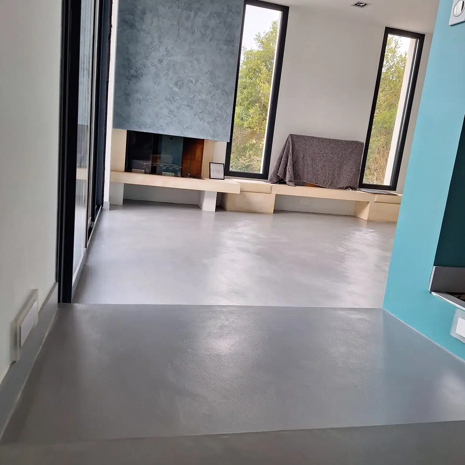 Sol en béton ciré dans un salon avec cheminée et fenêtres