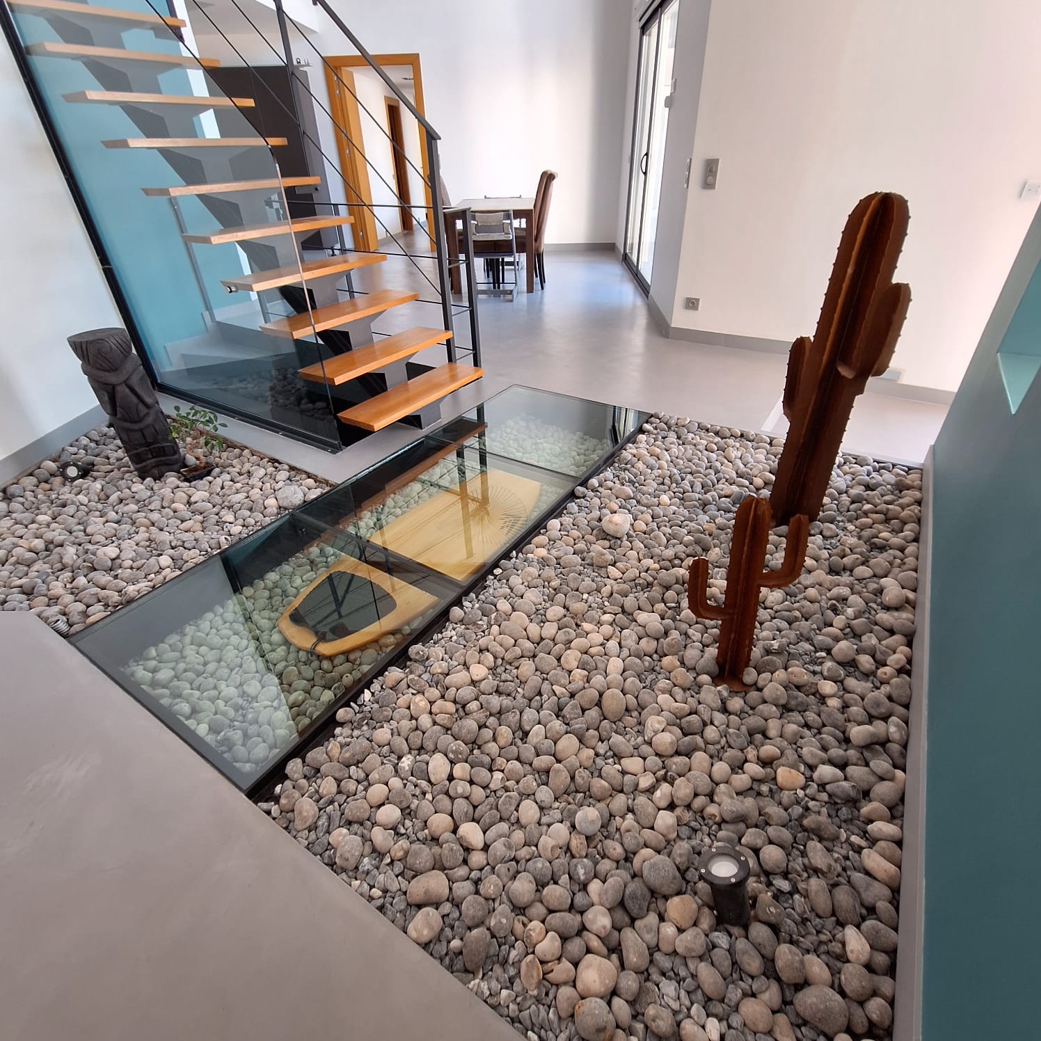 Sol en béton ciré dans un salon avec escalier et galets décoratifs