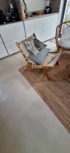 Sol en béton ciré dans un salon avec fauteuil et coussins décoratifs