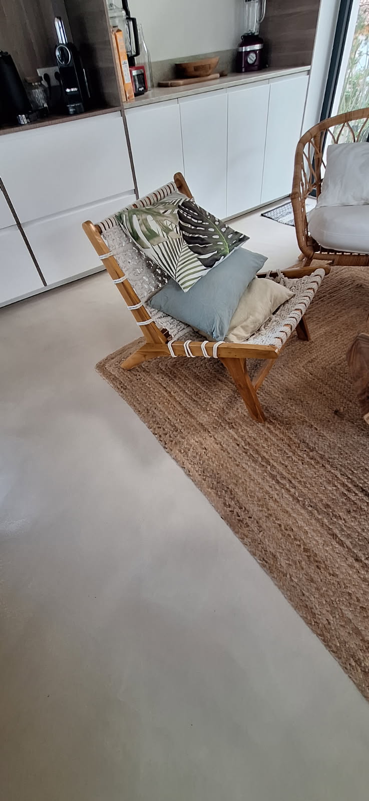 Sol en béton ciré dans un salon avec fauteuil et coussins décoratifs