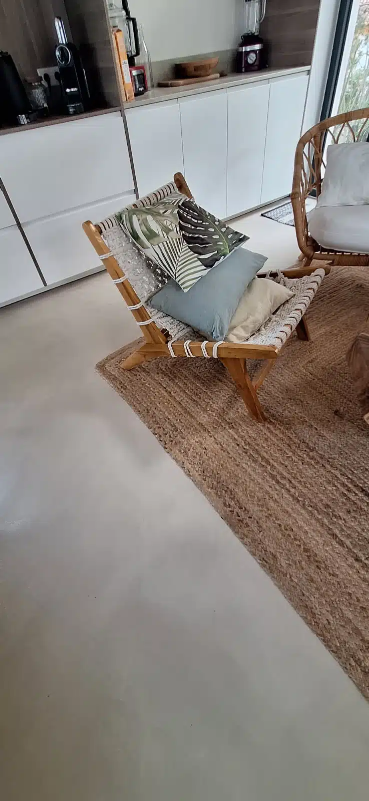 Sol en béton ciré dans un salon avec fauteuil et coussins décoratifs