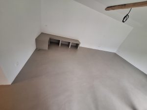 Sol en béton ciré sous des combles avec un meuble intégré
