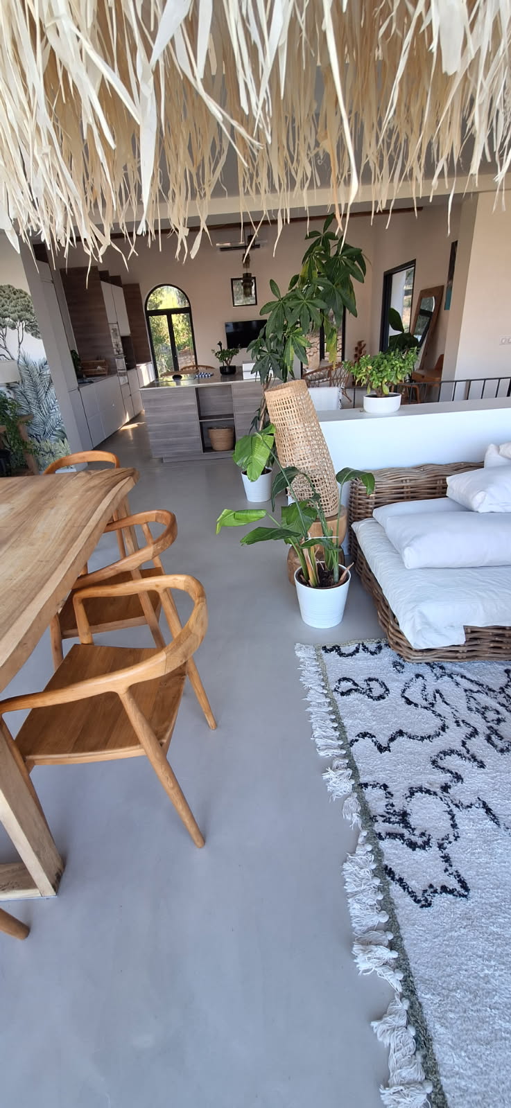 Intérieur moderne avec sol en béton ciré, plantes et mobilier en bois.
