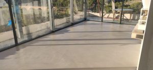 Vue d'un sol en béton ciré dans une véranda avec des fenêtres.