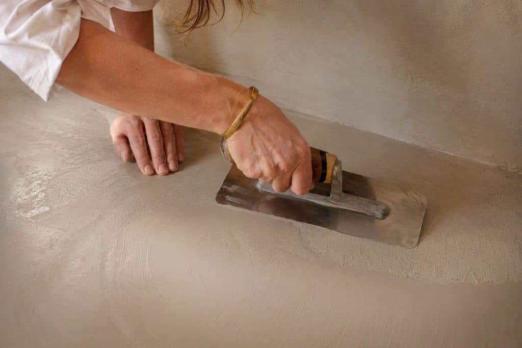 Artisane béton ciré appliquant la matière à la taloche inox - choisir son artisan en PACA