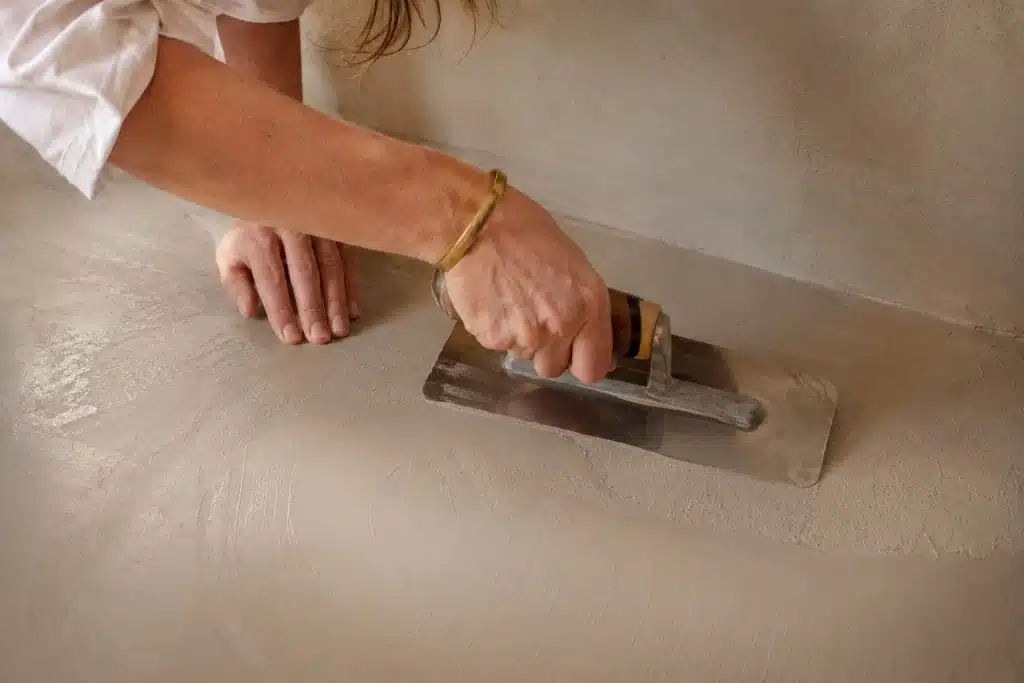 Artisane béton ciré appliquant la matière à la taloche inox - choisir son artisan en PACA