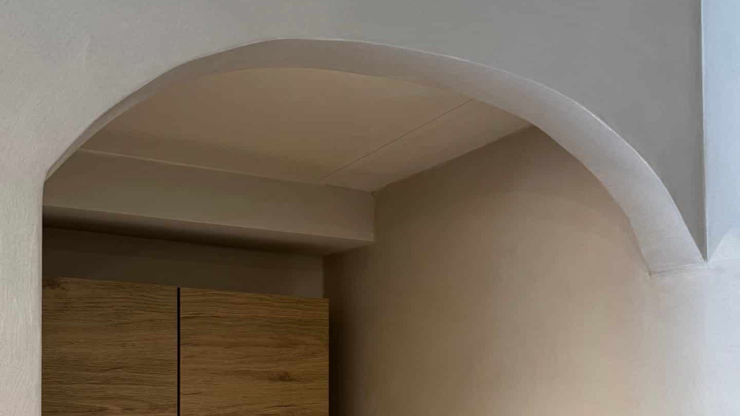 Arche intérieure recouverte de béton ciré clair, courbe continue sans joint au-dessus d’un meuble en bois — réalisation BTONBYSANDRA, béton ciré mural en PACA